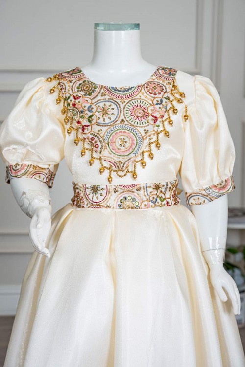 فستان بناتي طويل لون بيج فاتح مزين بتطريز ملون من الياقة و أطراف الأكمام و بحزام في الخصر