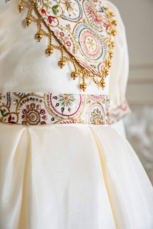 فستان بناتي طويل لون بيج فاتح مزين بتطريز ملون من الياقة و أطراف الأكمام و بحزام في الخصر