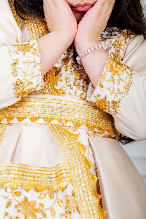 فستان تراثي بناتي لون بيج مزين بتطريز تراثي لون ذهبي ياقة قصة سبعة بأكمام طويلة و برباط في الخصر