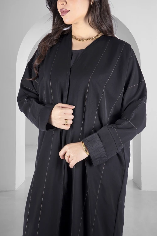 عباية سوداء انيقة أزرار قفل امامية خطوط طولية مطرزة باللون الذهبي اللامع و أكمام ضيقة مثنية بقماش مشجر انيق