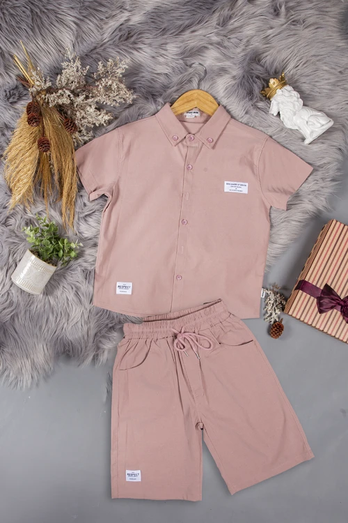 طقم ولادي قطعتين لون وردي أكمام قصيرة بياقة بأزرار قفل وجيب بطبعات من الامام وشورت بجيوب و رباط من الخصر