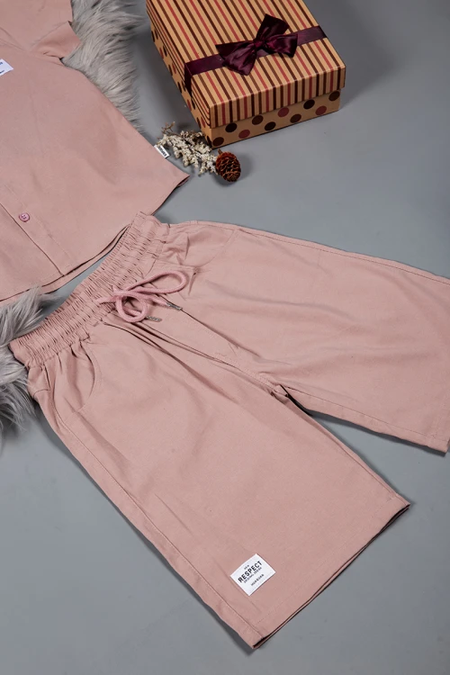 طقم ولادي قطعتين لون وردي أكمام قصيرة بياقة بأزرار قفل وجيب بطبعات من الامام وشورت بجيوب و رباط من الخصر
