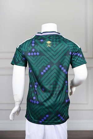 تيشيرت المنتخب السعودي شبابي لون أخضر داكن مع الشعار مزين بنمط هندسي و بزخارف ومنسوجات تراثية سعودية ياقة دائرية بلونين الأخضر و البنفسجي و بأكمام قصيرة