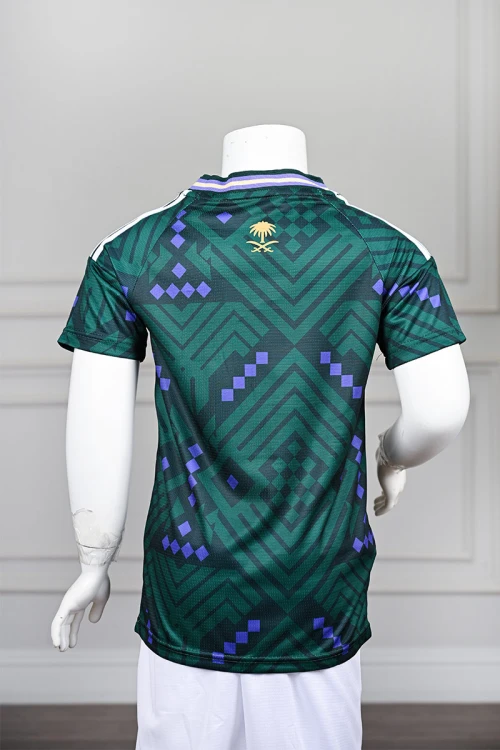 تيشيرت المنتخب السعودي شبابي لون أخضر داكن مع الشعار مزين بنمط هندسي و بزخارف ومنسوجات تراثية سعودية ياقة دائرية بلونين الأخضر و البنفسجي و بأكمام قصيرة