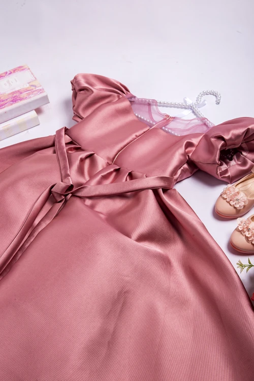 فستان بناتي أنيق لون وردي أكمام منفوشة وصدر قماش تل شفاف بتطريز كريستال فضي وفيونكة كبيرة على الخصر