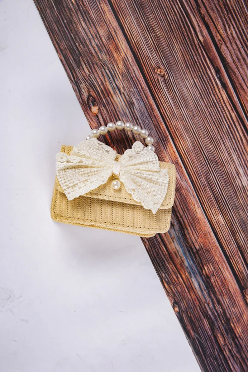 شنطة بناتي أنيقة لون ببيج مع فيونكة باللون السكري  مع مسكة مزينة باللؤلؤ وسلسال ذهبي