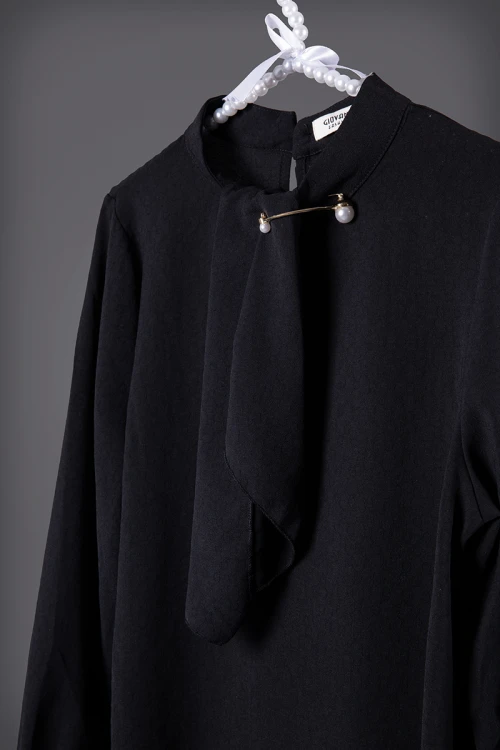 بلوزة نسائي أنيقة لون أسود أكمام طويلة و ياقة عالية مزينة بربطة وأكسسوار ذهبي عليه لؤلؤ من الأمام و زر قفل من الخلف