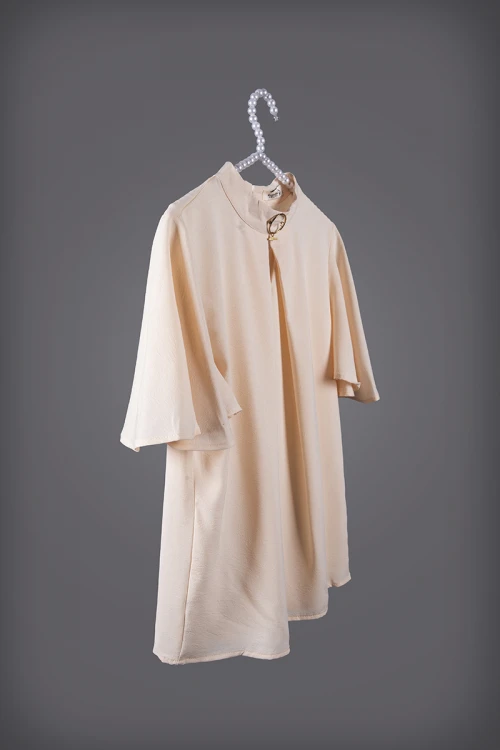 بلوزة نسائي أنيقة لون بيج أكمام قصيرة واسعة و ياقة عالية مزين بإكسسوار ذهبي من الأمام  وفتحة من الأمام