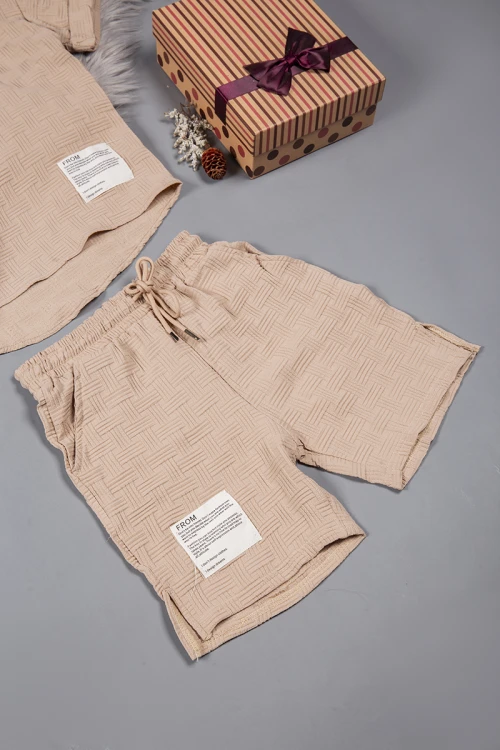 طقم ولادي قطعتين لون بيج أكمام قصيرة بياقة وأزرار قفل وطبعات من الامام وشورت بجيوب و رباط من الخصر