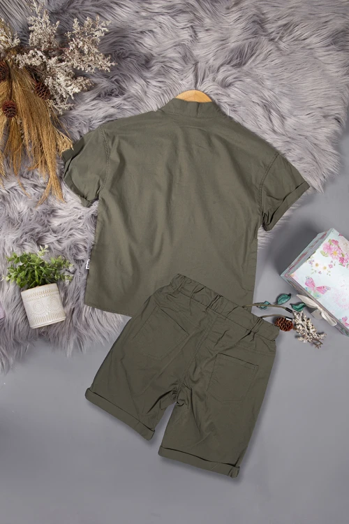 طقم ولادي قطعتين لون زيتي أكمام قصيرة بياقة عالية بأزرار قفل وجيب بطبعات من الامام وشورت بجيوب و رباط من الخصر