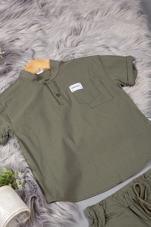 طقم ولادي قطعتين لون زيتي أكمام قصيرة بياقة عالية بأزرار قفل وجيب بطبعات من الامام وشورت بجيوب و رباط من الخصر