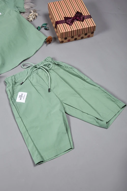 طقم ولادي قطعتين لون أخضر أكمام قصيرة بياقة عالية بأزرار قفل وجيب بطبعات من الامام وشورت بجيوب و رباط من الخصر