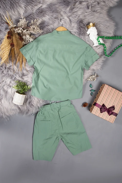 طقم ولادي قطعتين لون أخضر أكمام قصيرة بياقة عالية بأزرار قفل وجيب بطبعات من الامام وشورت بجيوب و رباط من الخصر