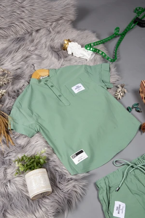 طقم ولادي قطعتين لون أخضر أكمام قصيرة بياقة عالية بأزرار قفل وجيب بطبعات من الامام وشورت بجيوب و رباط من الخصر