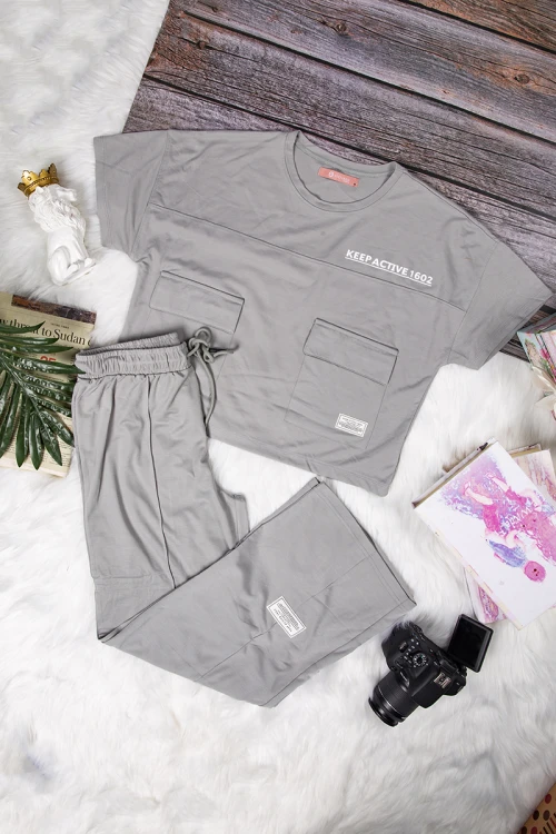 طقم نسائي أنيق قطعتين تي شيرت أكمام قصيرة بكتابات وجيوب من الأمام و بنطلون برباط على الخصر