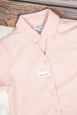 طقم بناتي أنيق قطعتين قميص كم قصير باللون الوردي الفاتح بأزرار من الأمام وبنطلون باللون الأسود واسع بجيوب من الأمام ورباط على الخصر