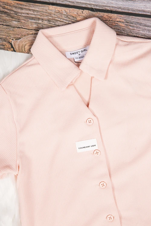 طقم بناتي أنيق قطعتين قميص كم قصير باللون الوردي الفاتح بأزرار من الأمام وبنطلون باللون الأسود واسع بجيوب من الأمام ورباط على الخصر