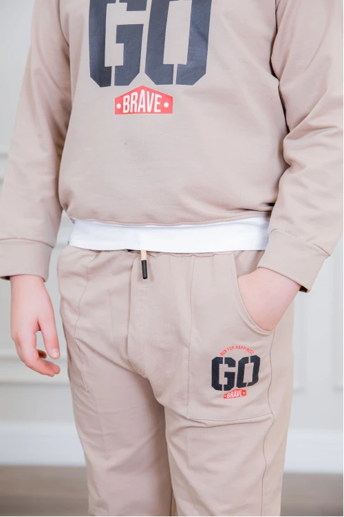 طقم ولادي أنيق قطعتين لون بيج أكمام طويلة مع كتابة أمامية و بنطلون بجيوب و مطاط من الأسفل