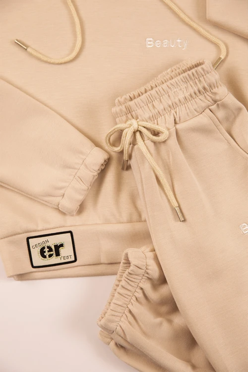 طقم بناتي شتوي قطعتين لون بيج بأكمام طويلة وقبعة متصلة مع بنطلون طويل بزم و رباط على الخصر