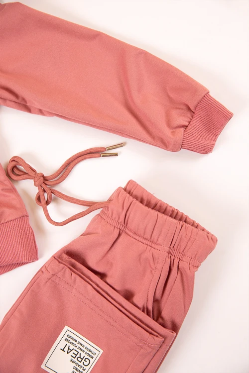 طقم بناتي شتوي قطعتين لون وردي هودي بكتابات من الأمام و أكمام طويلة مع بنطلون طويل بزم و رباط على الخصر