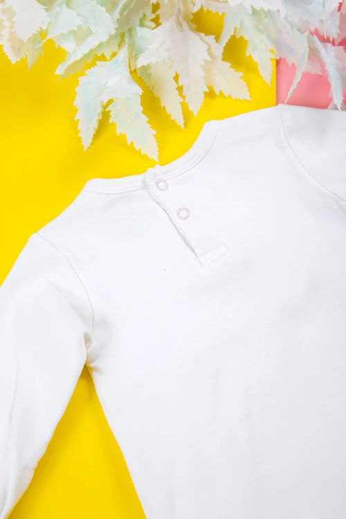 بربتوز بناتي أطفال لون أبيض مزين بزخرفة من الأمام ذو أكمام طويلة بزم و أزرار من الخلف و الأسفل