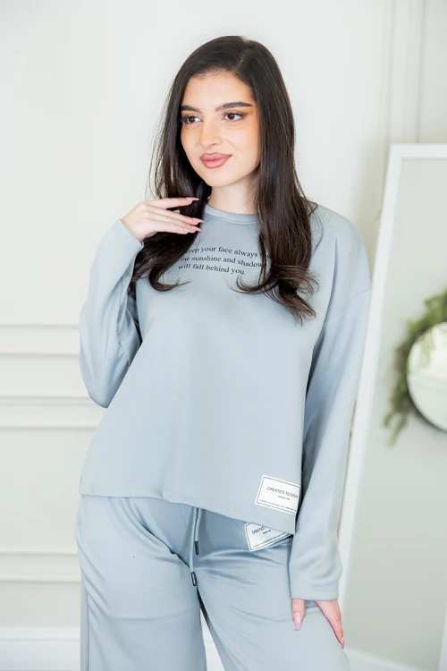 طقم نسائي شتوية قطعتين لون سماوي ذو أكمام طويلة بكتابة و طبعات من الأمام و ببنطلون برباط و زم من الخصر