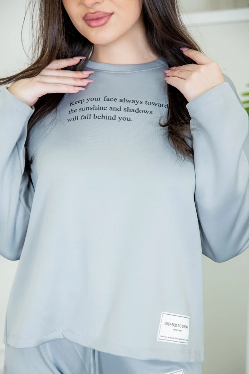 طقم نسائي شتوية قطعتين لون سماوي ذو أكمام طويلة بكتابة و طبعات من الأمام و ببنطلون برباط و زم من الخصر