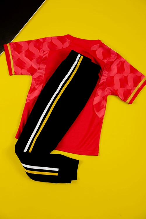 طقم ولادي رياضي قطعتين تيشيرت لون أحمر بأكمام قصيرة و بنطلون طويل لون أسود مخطط باللون الأبيض و الأصفر من الجانبين بزم من الخصر و الأسفل