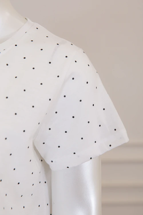 قميص نسائي طويل لون أبيض منقط بكتابة من الأمام و بياقة دائرية ذو أكمام قصيرة