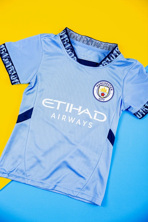 طقم ولادي رياضي قطعتين تيشيرت مانشستر سيتي بأكمام قصيرة و بنطلون طويل لون أسود مخطط باللون السماوي من الجانبين بزم من الخصر و الأسفل