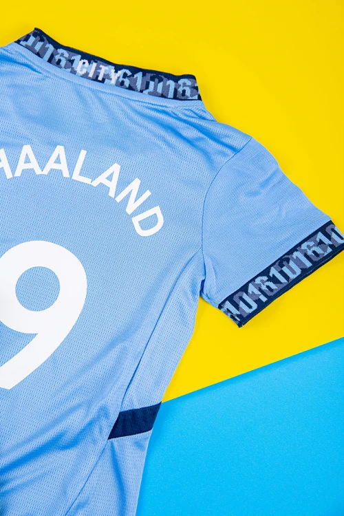 طقم ولادي رياضي قطعتين تيشيرت مانشستر سيتي بأكمام قصيرة و بنطلون طويل لون أسود مخطط باللون السماوي من الجانبين بزم من الخصر و الأسفل