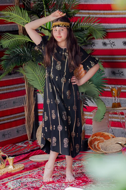 فستان بناتي لون أسود بأكمام قصيرة مزين بطبعات من شعار يوم التأسيس باللون الذهبي و رباط من الخصر