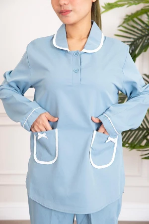 زي عاملة قطعتين لون سماوي بلوزة بياقة مطوية و أزرار و جيوب مزينة بفيونكة من الأمام  ذو أكمام طويلة و بنطلون طويل 