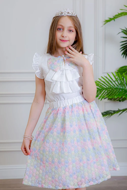 طقم تيور بناتي قطعتين بلوزة بلون أبيض مزينة بفيونكة ملونة من الأمام بدون أكمام و تـنورة ملونة