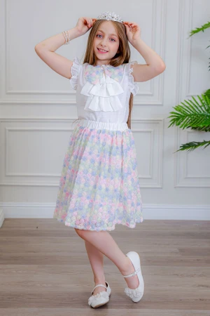 طقم تيور بناتي قطعتين بلوزة بلون أبيض مزينة بفيونكة ملونة من الأمام بدون أكمام و تـنورة ملونة