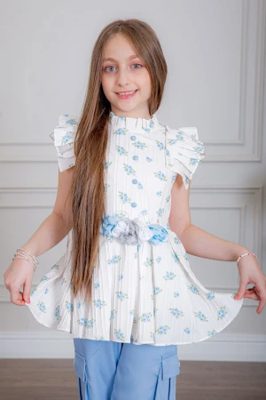 بدلة بناتي قطعتين بلوزة لون أبيض بياقة عالية بدون أكمام مزينة بورود سماوية و أزرار من الأمام و حزام في الخصر مع بنطلون طويل لون سماوي بجيوب من الجانبين