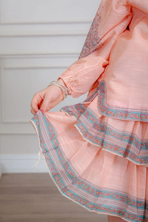 طقم تيور بناتي قطعتين لون خربزي بلوزة بياقة عالية و أزرار من الأمام ذو أكمام طويلة و تـنورة مزين بزخارف ملونة من الأطراف و الأكمام