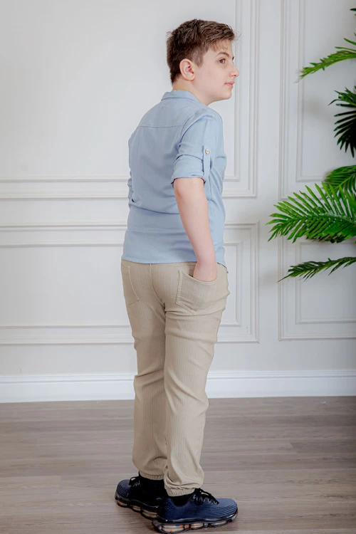 بدلة ولادي قطعتين قميص لون سماوي  بأزرار و جيب و كتابات من الأمام و بنطلون لون بيج بجيوب من الجانبين و الخلف و برباط في الخصر