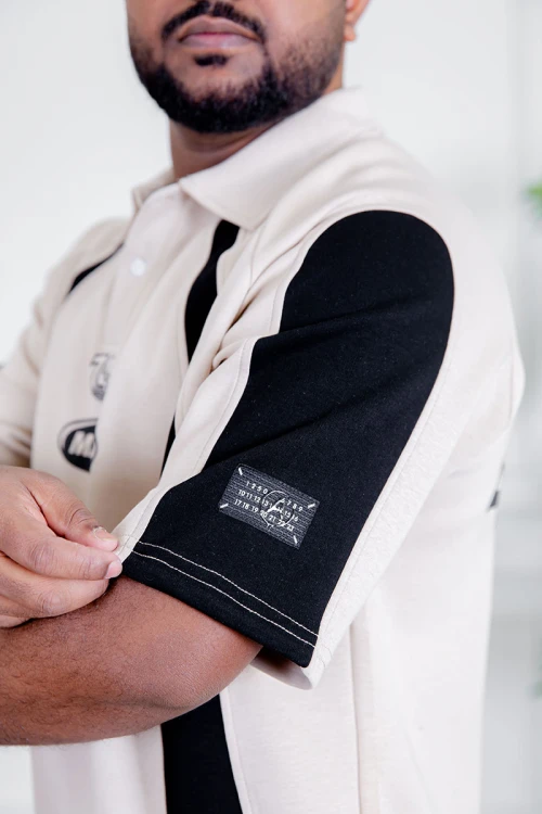 تيشيرت رجالي لون بيج فاتح و أسود ياقة مطوية بأزرار مزين بكتابات و طبعات من الأمام و الخلف