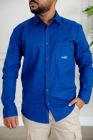 قميص رجالي لون أزرق كم طويل بأزرار من الأمام و الجانبين و بجيب من الأمام 