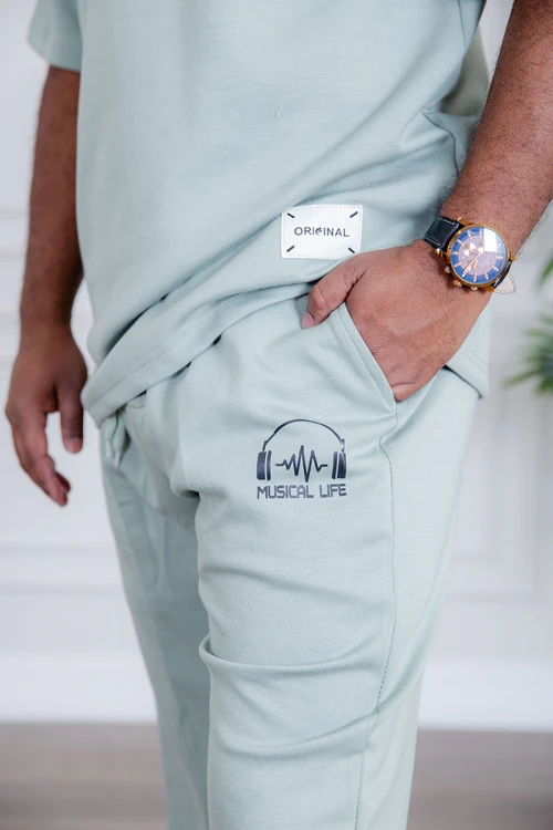 طقم رجالي قطعتين لون تيفاني فاتح تيشيرت بكتابات و طبعات مع بنطلون طويل بجيوب من الجانبين و الخلف و برباط في الخصر