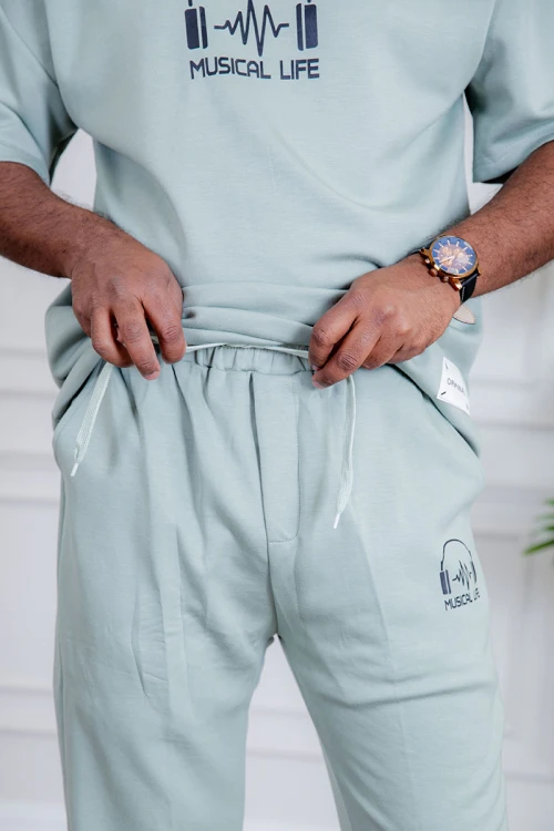 طقم رجالي قطعتين لون تيفاني فاتح تيشيرت بكتابات و طبعات مع بنطلون طويل بجيوب من الجانبين و الخلف و برباط في الخصر