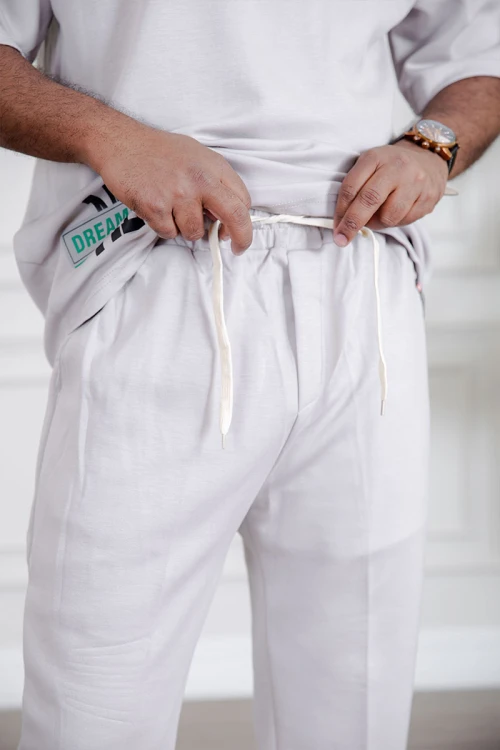 طقم رجالي قطعتين لون أبيض تيشيرت بكتابات مع بنطلون طويل بجيوب من الجانبين و الخلف و برباط في الخصر