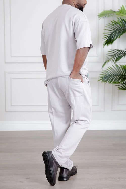 طقم رجالي قطعتين لون أبيض تيشيرت بكتابات مع بنطلون طويل بجيوب من الجانبين و الخلف و برباط في الخصر