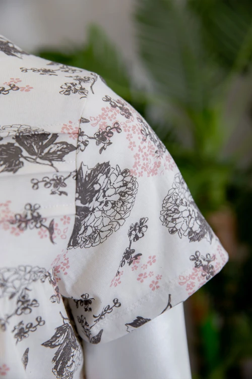 قميص نسائي لون أبيض مشجر بياقة دائرية و أزرار من الأمام ذو أكمام قصيرة