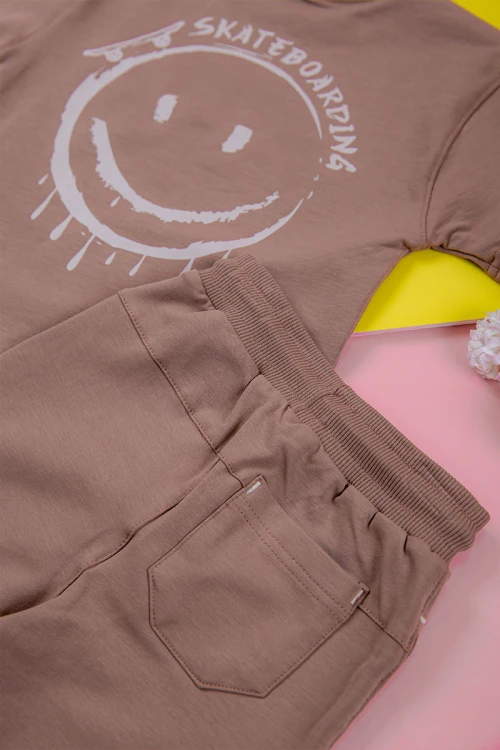 ترنج ولادي قطعتين لون لحمي تيشيرت برسومات و كتابات من الأمام و شورت برباط في الخصر و جيوب من الجانبين و الخلف