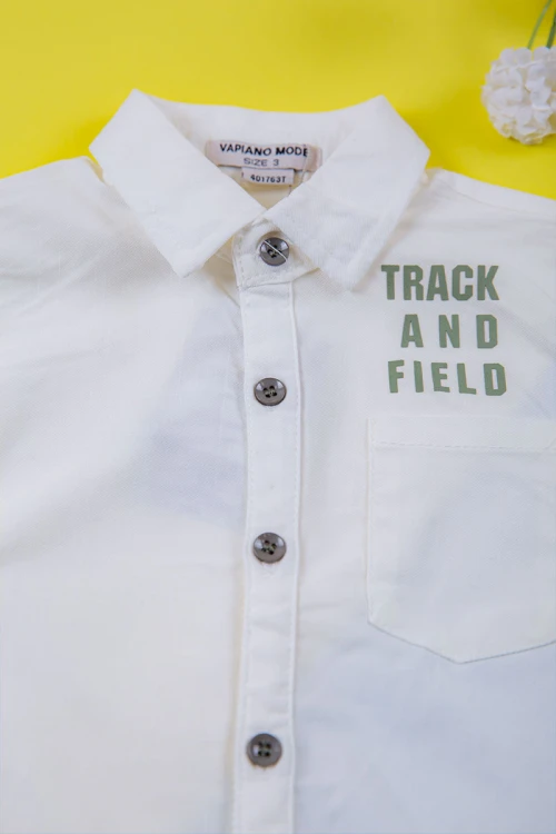 طقم ولادي قطعتين قميص أبيض مشجر باللون السماوي ياقة مطوية و أزرار من الأمام و شورت لون سماوي برباط في الخصر و جيوب من الجانبين