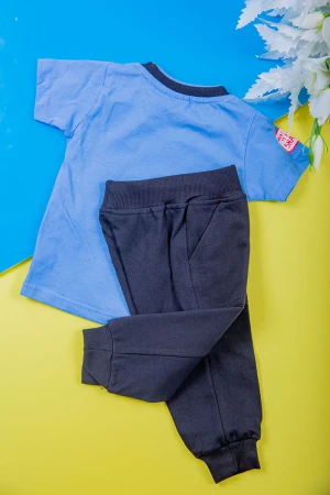 طقم ولادي قطعتين تيشيرت لون سماوي مزين بكتابات و رسومات من الأمام مع بنطلون طويل لون أسود بجيوب من الجانبين و زم في الأسفل 