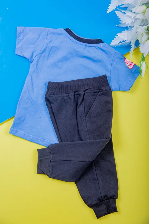 طقم ولادي قطعتين تيشيرت لون سماوي مزين بكتابات و رسومات من الأمام مع بنطلون طويل لون أسود بجيوب من الجانبين و زم في الأسفل