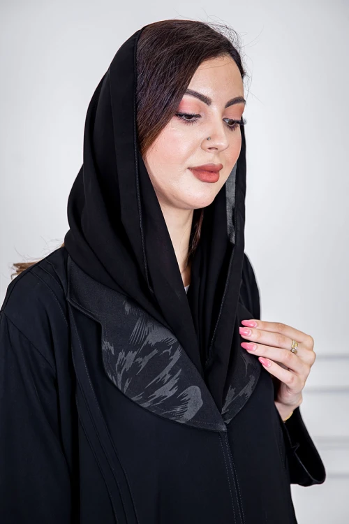 عباية نسائية أنيقة لون أسود ياقة مطوية مزينة بنقوش في الياقة و أطراف الأكمام بأزرار من الأمام مع طرحة
